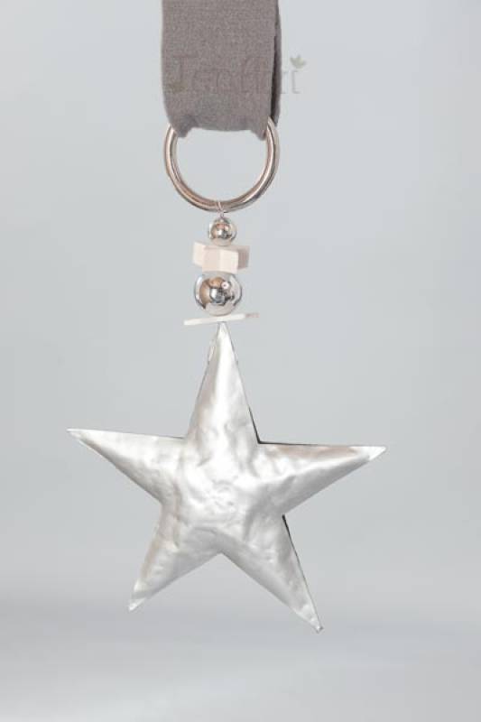 Fensterdekoration mit einem silberfarbenem Stern aus Metall. Der Stern hängt an einem weißem Band.